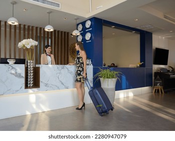 Caucasian woman traveller with baggage standing at hotel guest check-in counter and talking with Asian young attractive female receptionist. Travelling, holiday and vacation concept - Shutterstock ID 2280947079