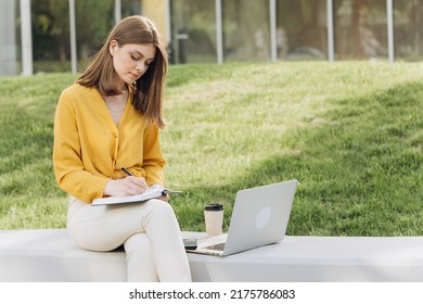 Caucasian Woman University Student Learning Online Using Laptop Computer, Taking Notes, Watching Webinar Or Virtual Education Remote Class Studying Outdoor Sitting Outside Uni Campus Area.