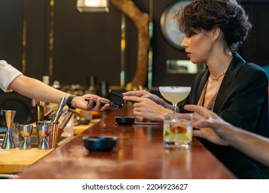 Caucasian Woman Using Mobile Banking Application On Smartphone Scan QR Code Making Online Payment While Hangout Party At Restaurant Bar. Electronic Banking And Contactless Payment Technology Concept.