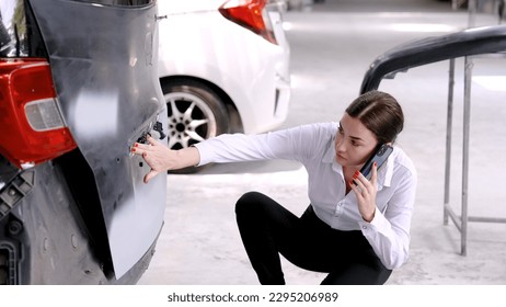 Caucasian woman using a mobile phone to call an insurance claim in an accident where the car was rear-ended to explain the damage to the car in order to prepare for repairs. in the auto repair shop - Shutterstock ID 2295206989