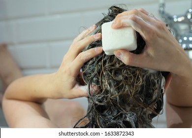 Caucasian woman washes her brown hair with shampoo bar or soap, zero waste concept - Shutterstock ID 1633872343