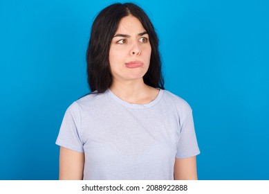 Caucasian woman wearing blue T-shirt over blue backgroundmaking grimace and crazy face, screaming out of control, funny lunatic expressing freedom and wild.