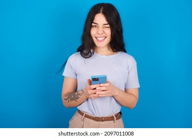 Caucasian woman wearing blue T-shirt over blue background   taking a selfie  celebrating success