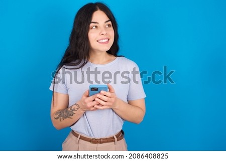 Caucasian woman wearing blue T-shirt over blue background holding in hands showing new cell