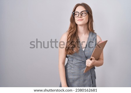Caucasian woman wearing glasses and business clothes smiling looking to the side and staring away thinking. 