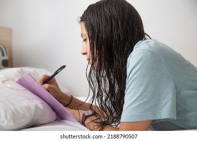 Caucasian Woman Wearing Only A T-shirt Writing In Her Notebook On The Bed With White Sheets