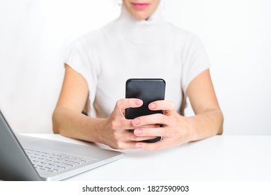 Caucasian Woman Wearing White Clothes Using An Smart Phone In The Office. Concept Of New Technologies And Distraction