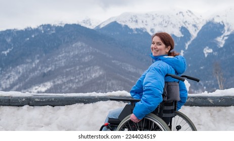 Mujer caucásica en silla de ruedas viaja en las montañas en invierno.