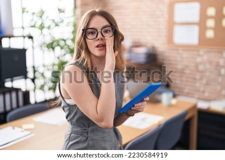 Caucasian woman working at the office wearing glasses hand on mouth telling secret rumor, whispering malicious talk conversation 