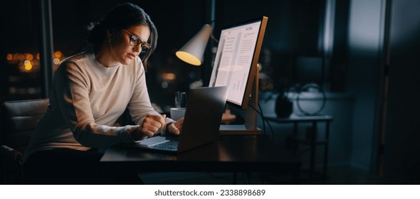 Caucasian woman works late from her home office, typing her ideas on her laptop. Professional business woman working late hours, maintaining a work-life balance and excelling in digital marketing. - Powered by Shutterstock