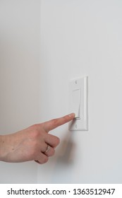Caucasian womans hand flicking a light switch on and off