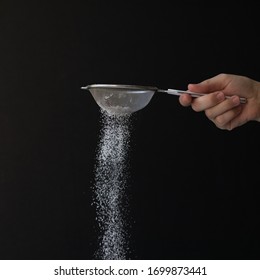 Caucasian woman's hand sprinkles sugar through sieve, on solid black background. Process of preparing a dessert. Making food, bakery cooking class concept. - Powered by Shutterstock