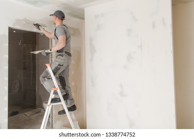 Caucasian Worker In His 30s Patching Drywall Inside Newly Developed House.