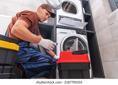 Caucasian Worker At His 40s Fixing And Unclogging The Washing Machine In His Client’s Laundry Room. Professional Home Repair Services Theme.