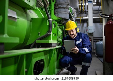 Caucasian worker or serviceman checking diagnostics of large industrial generator in power plant. - Shutterstock ID 2187609959