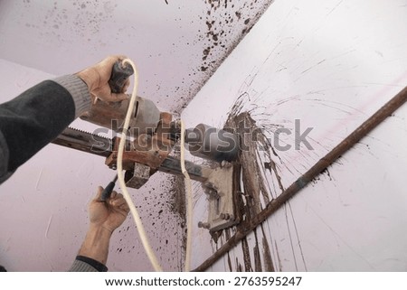 Caucasian worker using concrete core drilling machine. 