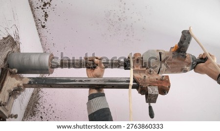 Caucasian worker using concrete core drilling machine. 