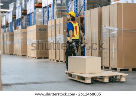 caucasian worker in a warehouse using hand pallet stacker to transport moving pallets good cargo, hardworking male staff in safety uniform vest at work. Hand pallet truck jack in warehouse