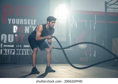 Caucasian Young Active Handsome Sportsman Exercise In Fitness Stadium. Attractive Athlete Muscular Male Practice Using Battle Rope Make Double Wave To Lose Weight And Build Muscle In Gym Health Club.