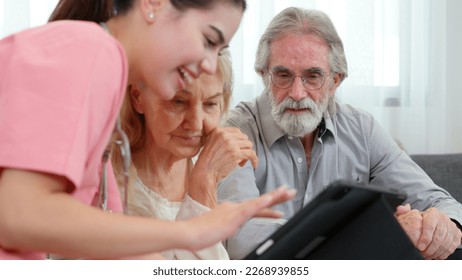 Caucasian young adult nurse is visiting elderly couple and holding a tablet to show medical records. Female caregiver is explaining result of medical examination and treatment to senior grandparents.  - Powered by Shutterstock