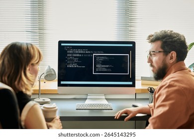 Caucasian young adult woman and Caucasian young adult man collaborating at desk, analyzing neural network code displayed on computer monitor, discussing software development process - Powered by Shutterstock - Get 15% off with code: PIKWIZARD15