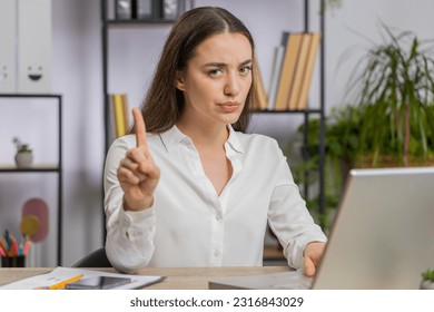 Caucasian young business woman working on laptop computer shakes finger, saying No be careful scolding and giving advice to avoid danger mistake disapproval sign at office. Confident freelancer girl - Powered by Shutterstock