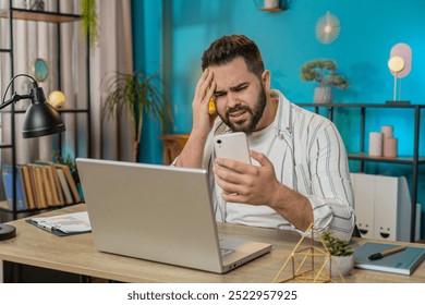 Caucasian young businessman using smartphone typing browsing loses becoming surprised sudden lottery results bad news, fortune loss fail at home office desk workplace. Freelancer worker man. Lifestyle - Powered by Shutterstock