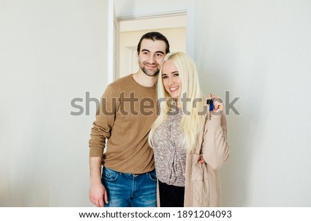 caucasian young couple showing keys and looking at camera, embracing, happy family celebrating relocation day, moving at new home, property owners,