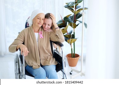 Caucasian Young Daughter Hug With Love And Care For Her Mother In White Headscarf Is Sitting On Wheelchair After Chemotherapy. Elderly Mother Is Suffering From Cancer Or Leukemia Patient.