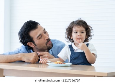 Caucasian Young Father With Beard Looking And Cheer Up Little Cute Daughter Trying To Eat Spaghetti With Spoon By Herself At Home And Adorable Kid Girl Enjoy Eating With Face Is Mess Up With Ketchup