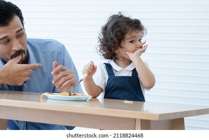 Caucasian Young Father With Beard Looking And Cheer Up Little Cute Daughter Trying To Eat Spaghetti With Spoon By Herself At Home And Adorable Kid Girl Enjoy Eating With Face Is Mess Up With Ketchup