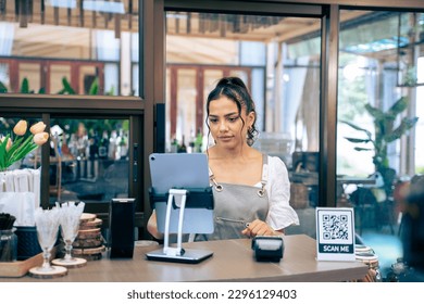 Caucasian young female barista or waitress working in the coffeehouse. Attractive beautiful entrepreneur woman wearing apron, smiling checking sale order with confidence at coffee shop restaurant cafe