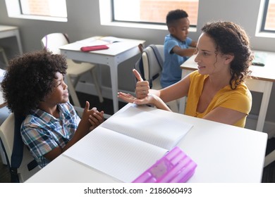 Caucasian young female teacher teaching sign language to african american elementary boy in class. unaltered, education, childhood, learning, teaching, disability, communication and school concept. - Powered by Shutterstock