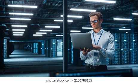 Caucasian Young Male IT Specialist Using Laptop, Standing in Data Center. Skilful Man Works on Web Services. Cloud Computing, Server Analytics, Cyber Security Maintenance