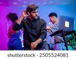 Caucasian young man artist DJ mixing and scratching music mixer controller. Attractive male musician DJ having fun mixing music on console touching buttons and playing electronic music at neon party.