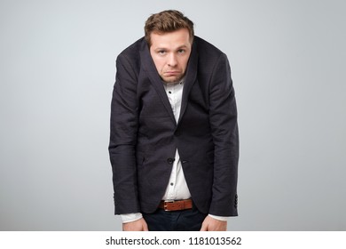 Caucasian Young Man In Too Big Suit. He Is Offended And Looking Stressed. Looking Silly In A Suit Of Wrong Size