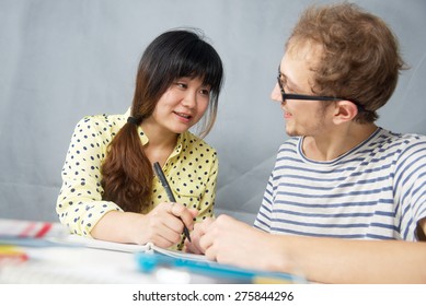 Caucasian Young Man Talking With A Chinese Girl Is Language Teacher