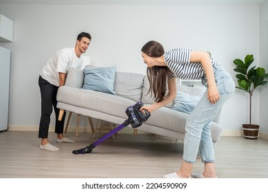 Caucasian Young Man And Woman Cleaning Living Room Together At Home. Beautiful Lovely Couple Male And Female Moving Sofa For Vacuuming Messy Dirty Floor For Housekeeping Housework And Chores In House.