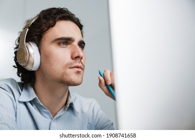 Caucasian Young Serious Businessman In Headphones Working On Computer In Office