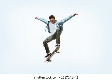 Caucasian young skateboarder riding isolated on a white studio background. Man in casual clothing training, jumping, practicing in motion. Concept of hobby, healthy lifestyle, youth, action, movement. - Powered by Shutterstock