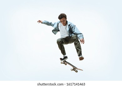 Caucasian young skateboarder riding isolated on a white studio background. Man in casual clothing training, jumping, practicing in motion. Concept of hobby, healthy lifestyle, youth, action, movement. - Powered by Shutterstock