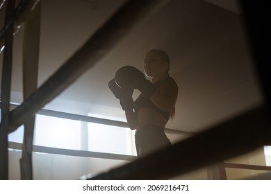 Caucasian Young Sporty Woman With Brunette Hair Practicing Inside Boxing Ring. Female Athlete is Training in Gym, doing a Shadow Fight, Preparing for a Competition - Powered by Shutterstock