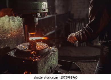 caucasian young strong blacksmith working with open fire in furnace. The blacksmith forging hot iron in workshop