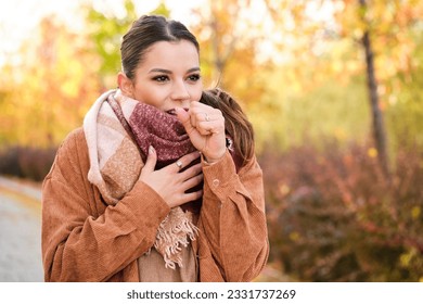 Caucasian young woman coughing during autumn.