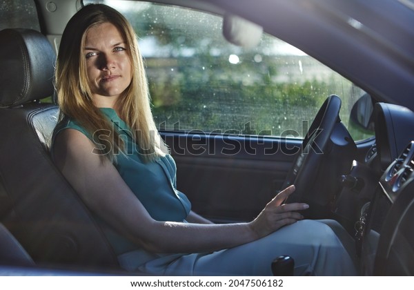 Caucasian young\
woman drives car in summer\
day.