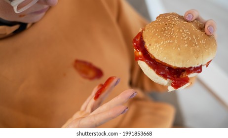 Caucasian Young Woman Eating Burger And Getting Dirty In Ketchup. Sloppy Girl