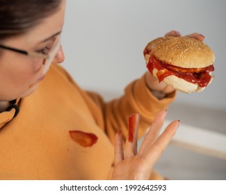 Caucasian Young Woman Eating Burger And Getting Dirty In Ketchup. Sloppy Girl