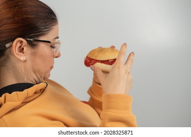 Caucasian Young Woman Eating Burger And Getting Dirty In Ketchup. Sloppy Girl