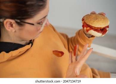 Caucasian Young Woman Eating Burger And Getting Dirty In Ketchup. Sloppy Girl