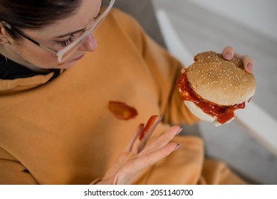 Caucasian Young Woman Eating Burger And Getting Dirty In Ketchup. Sloppy Girl